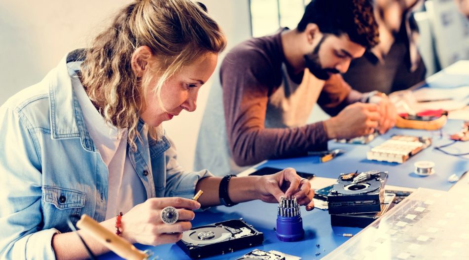 Junge Menschen arbeiten an Festplatten für Computer mit feinen Werkzeugen. Junge Menschen arbeiten an Festplatten für Computer mit feinen Werkzeugen.
