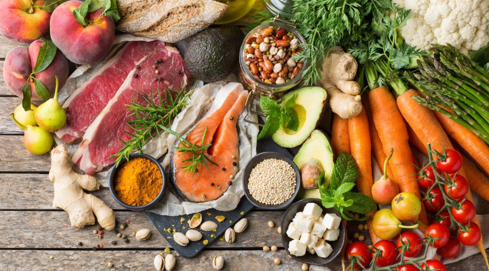 Frische Lebensmittel auf einem Holztisch: Obst, Gemüse, Fleisch, Lachs, Käse, Brot, Gewürze, Nüsse, Quinoa und Kräuter. Frische Lebensmittel auf einem Holztisch: Obst, Gemüse, Fleisch, Lachs, Käse, Brot, Gewürze, Nüsse, Quinoa und Kräuter.